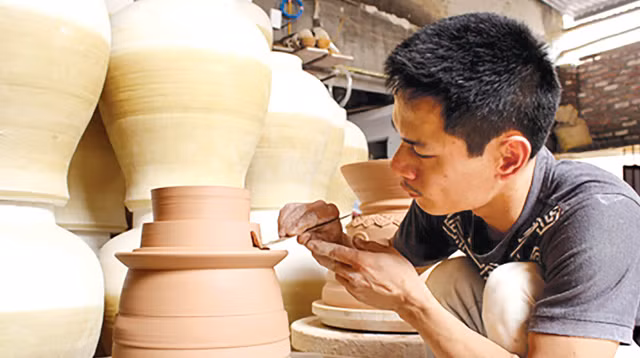 Anh Phạm Anh Đạo đang hoàn thiện sản phẩm gốm của mình. Ảnh: Q.L