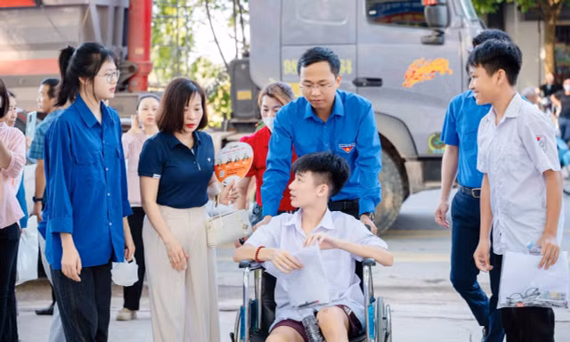 Tình nguyện viên ở Trường THPT Việt Yên số 2 hỗ trợ thí sinh ngồi xe lăn vào phòng thi.