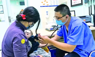 Bác sĩ Hùng khám cho bệnh nhi. Ảnh: Thái Hà 