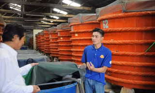 Nhân viên một cơ sở nhà thùng tại Phú Quốc (áo sẫm) cho biết về quy trình sản xuất nước mắm. Ảnh: CK