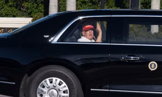 Tổng thống Mỹ Donald Trump vẫy tay khi đang ngồi trên chiếc limousine trở về khu biệt thự và sân golf của ông ở West Palm Beach ngày 8/3. (Ảnh: AP)
