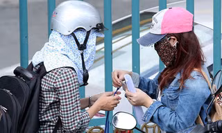 Sinh viên H.N (phải) gửi thẻ sinh viên nhờ phóng viên thi hộ ngay trước cổng trường - Ảnh: Đào Ngọc Thạch