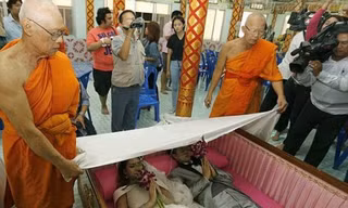  Một cặp đôi nằm trong quan tài thực hiện nghi lễ. Các nhà sư phủ vải trắng lên họ. (Nguồn: Daily Mail)