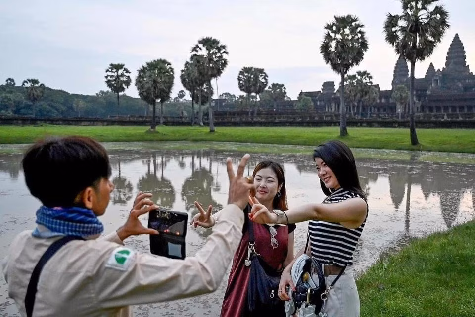 Hướng dẫn viên Campuchia giúp du khách Trung Quốc chụp ảnh tại quần thể đền Angkor Wat, tỉnh Siem Reap, năm 2024. Ảnh: CFP.