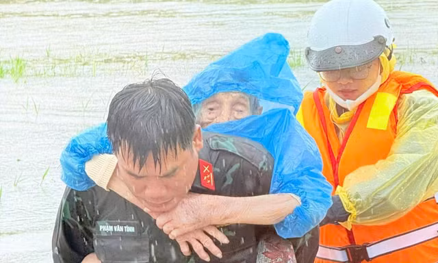 Lực lượng chức năng di dời người dân vùng ngập đến nơi an toàn.