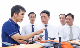 Anh Phùng Thanh Trinh (bìa trái, Đồng sáng lập và Điều hành start-up XBStation) giới thiệu về giải pháp điều khiển thiết bị bay không người lái với nguyên Bộ trưởng Bộ Khoa học và Công nghệ Nguyễn Mạnh Hùng Ảnh: Giang Thanh 