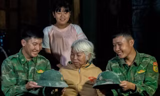 Hai người lính trẻ chụp ảnh lưu niệm, chia tay gia đình cụ Ngô Thị Lỡ với những chiếc mũ cối dính xi măng, có chiếc đứt dây Ảnh: Lê Văn Chương 