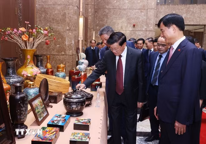 Tổng Bí thư, Chủ tịch nước Lào Thongluon Sinsoulith tham quan không gian trưng bày các sản phẩm thủ công mỹ nghệ làng nghề truyền thống của Hà Nội. (Ảnh: Văn Điệp/TTXVN)