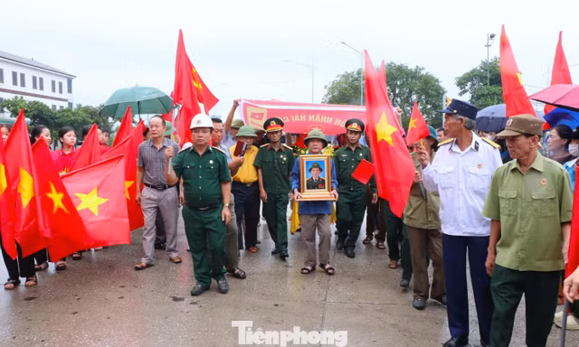 Hàng trăm người đội mưa, cầm cờ Tổ quốc đón liệt sĩ trở về sau 59 năm