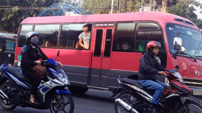Một phụ xe nhô đầu ra cửa sổ để chèo kéo, “bắt” khách trên Quốc lộ 13.