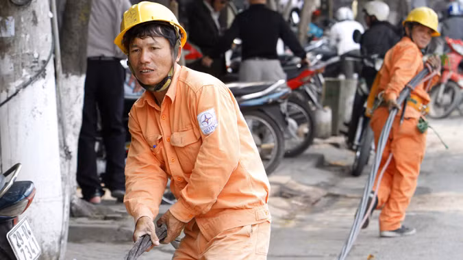 Giá điện tăng dưới 7%, EVN sẽ được tự tăng giá (công nhân điện lực đang kéo đường dây điện trên đường Giải Phóng - Hà Nội). Ảnh: Ngọc Châu