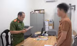 Ông L.V.Q (bìa phải) nghe quyết định khởi tố bị can, khởi tố vụ án trốn thuế -Ảnh: TL