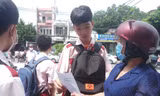 Giáo viên và thí sinh trao đổi bài thi môn Ngữ văn tại điểm thi trường THCS Nguyễn Trãi, Gò Vấp