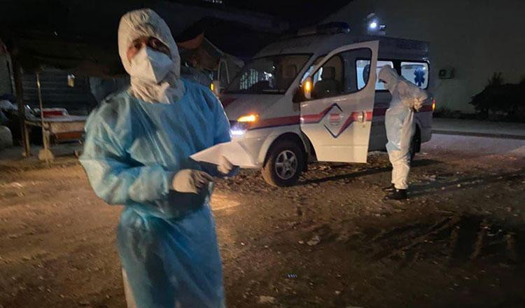 Các quan chức y tế và một xe cấp cứu chờ đợi để thu thập các bệnh nhân COVID-19. (Rasmei News)