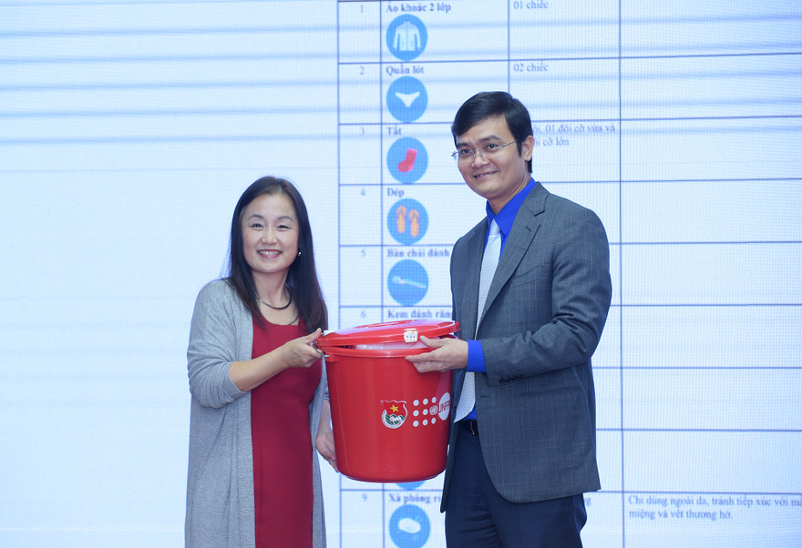 Anh Bùi Quang Huy tiếp nhận bộ đồ thiết yếu cho người cao tuổi ứng phó với lũ lụt từ bà Naomi Kitahara. Ảnh: Xuân Tùng