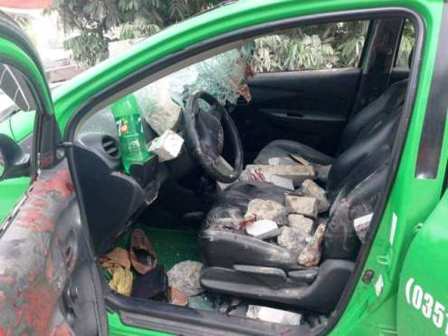 Chiếc taxi hư hại nặng vì bị người dân ném gạch đá.