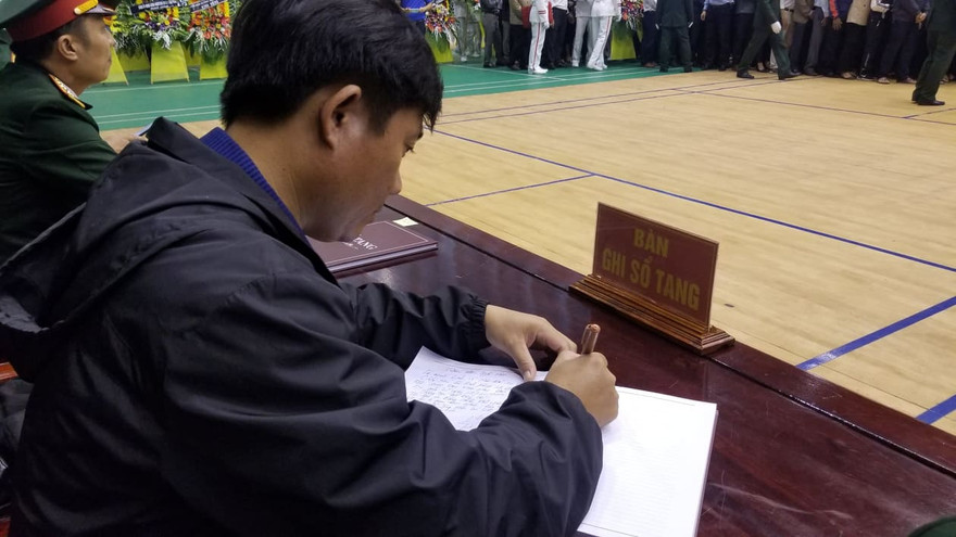 Người dự lễ viếng ghi sổ tang trong buổi tiễn đưa 22 liệt sĩ về nơi an nghỉ cuối cùng.