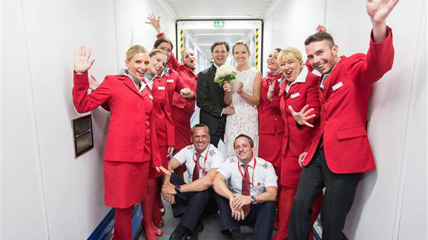 Cô dâu, chú rể tươi cười chụp ảnh cùng các tiếp viên hàng không trên máy bay