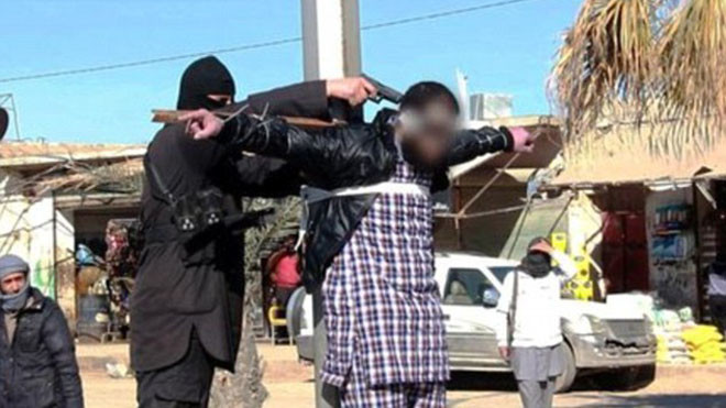 Phiến quân IS chĩa súng vào đầu nạn nhân bị trói trên thập giá giữa phố ở Raqqa.