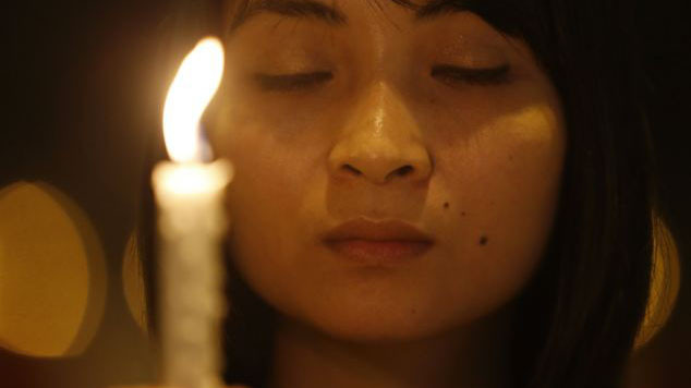 Một cô gái cầm nến cầu nguyện cho chiếc máy bay mất tích