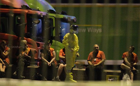 Một nhân viên của đội phá bom và chất độc hóa học trong trang phục bảo hộ bên ngoài văn phòng phân loại bưu kiện Stokke.