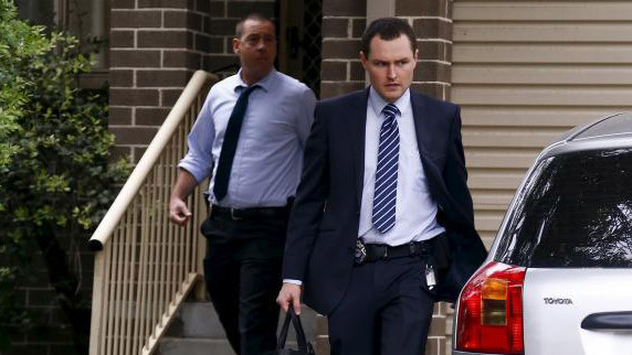 Nhân viên cảnh sát ra khỏi một ngôi nhà sau khi bắt giữ các nghi phạm