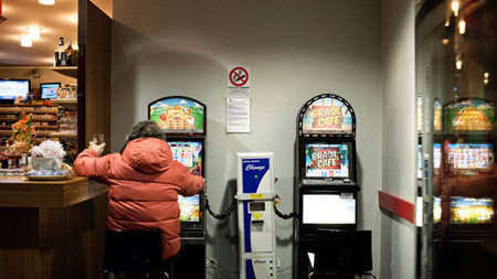 Một người đang mê mẩn bên máy đánh bạc trong quán bar.