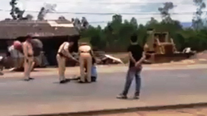 CSGT thuyết phục anh T. đang ôm con nằm giữa đường QL1A đòi tự vẫn (ảnh chụp từ Clip)