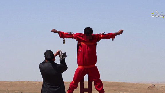 Nạn nhân mặc áo cam bị trói trên khung chữ thập giữa sa mạc.