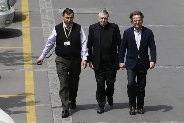 Linh mục John O’Reilly (giữa) được nhân viên tòa án và luật sư đưa vào buổi xét xử