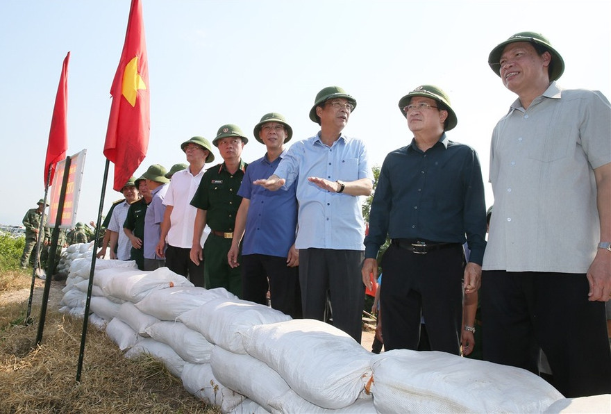 Phó Thủ tướng Trịnh Đình Dũng nghe báo cáo của Bí thư Tỉnh ủy Nguyễn Văn Đọc về phương án bảo vệ, gia cố tuyến đê Hà Nam (TX. Quảng Yên). Ảnh: BQN