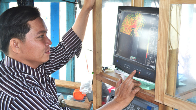 Anh Trần Công Tăng bên máy dò ngang lắp đặt trên tàu cá