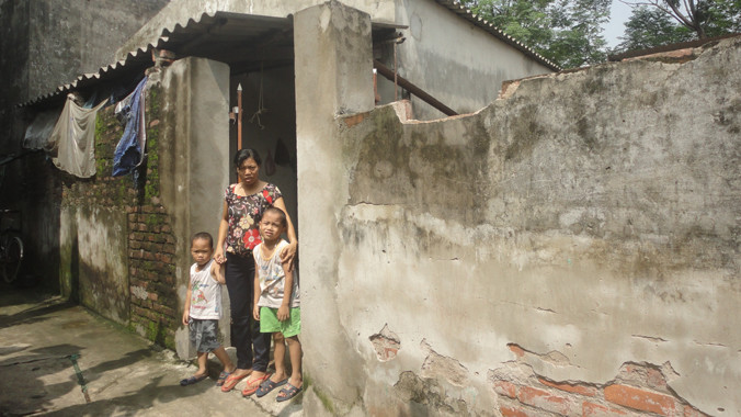 Chị Nhâm và hai con trước căn nhà xuống cấp. Ảnh: K.N