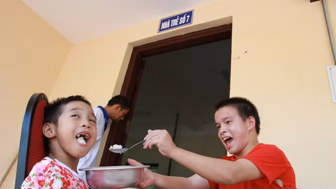 Hai em nhỏ tự đút cơm cho nhau ăn rất ngon lành. Ảnh: Minh Đức