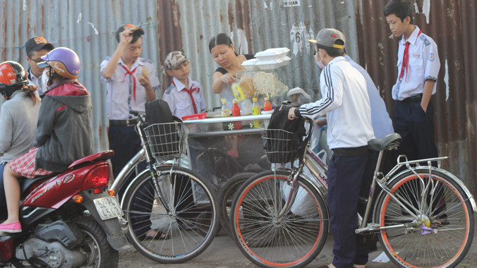 Học sinh Trường THCS Hoàng Hoa Thám phải mua bánh mì, xôi… ngay tại cổng trường ăn cho kịp giờ học buổi sáng. Ảnh: Ngô Đào