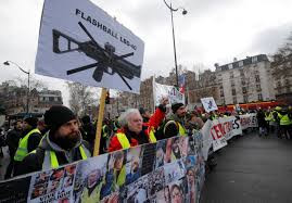 Người biểu tình 'Áo vàng' mang theo biểu ngữ phản đối, cùng ảnh của các nạn nhân bị thương khi đụng độ với cảnh sát