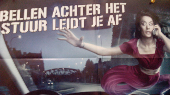 Một tấm áp phích cảnh báo nguy hiểm khi vừa lái xe vừa nghe điện thoại