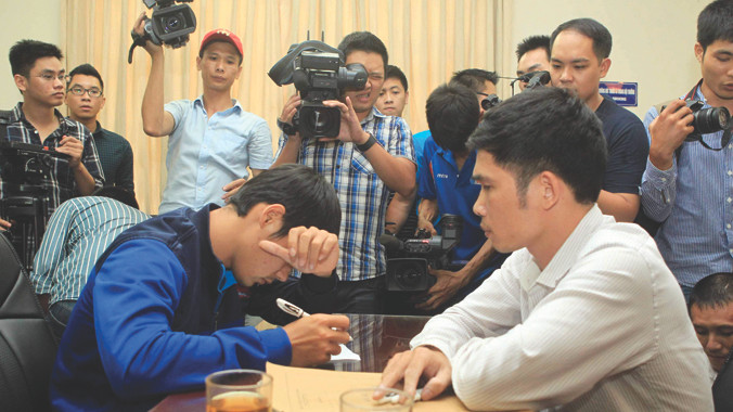 Hậu vệ Phan Lưu Thế Sơn (Đồng Nai) che mặt viết tường trình tại cơ quan công an trước ống kính của báo chí. Ảnh: Tuấn Tú