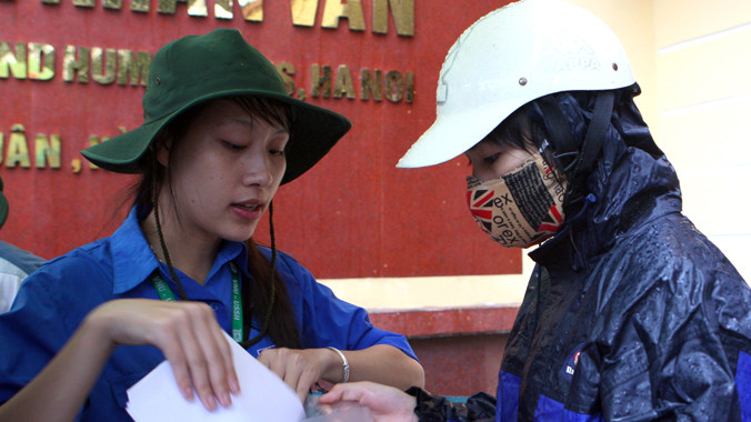 Tình nguyện viên tư vấn giấy tờ cho thí sinh đến đăng ký dự thi tại điểm Trường ĐH KHXH&NV. Ảnh: Xuân Tùng