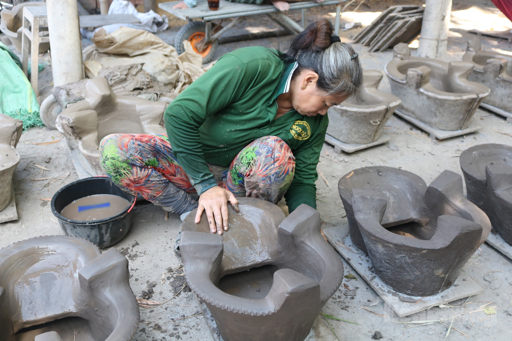 Chưa dừng lại, người thợ còn phải cạo, làm bóng chiếc lò đất trước khi đem đi nung. Các công đoạn làm lò đất đều được thực hiện bằng tay trần, do đó bàn tay ai nấy đều bị nước ăn hư hết móng, nhất là các chị em phụ nữ - Ảnh: Kim Hà. Chưa dừng lại, người thợ còn phải cạo, làm bóng chiếc lò đất trước khi đem đi nung. Các công đoạn làm lò đất đều được thực hiện bằng tay trần, do đó bàn tay ai nấy đều bị nước ăn hư hết móng, nhất là các chị em phụ nữ - Ảnh: Kim Hà.