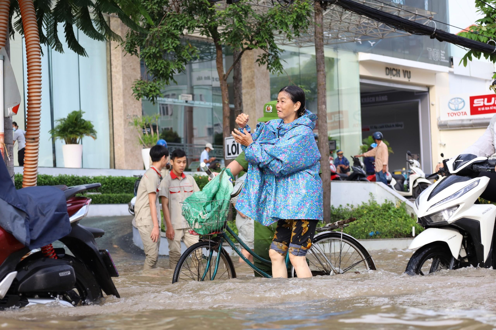 Một người phụ nữ đi chợ được lực lượng hỗ trợ dẫn giúp xe đạp. Một người phụ nữ đi chợ được lực lượng hỗ trợ dẫn giúp xe đạp.