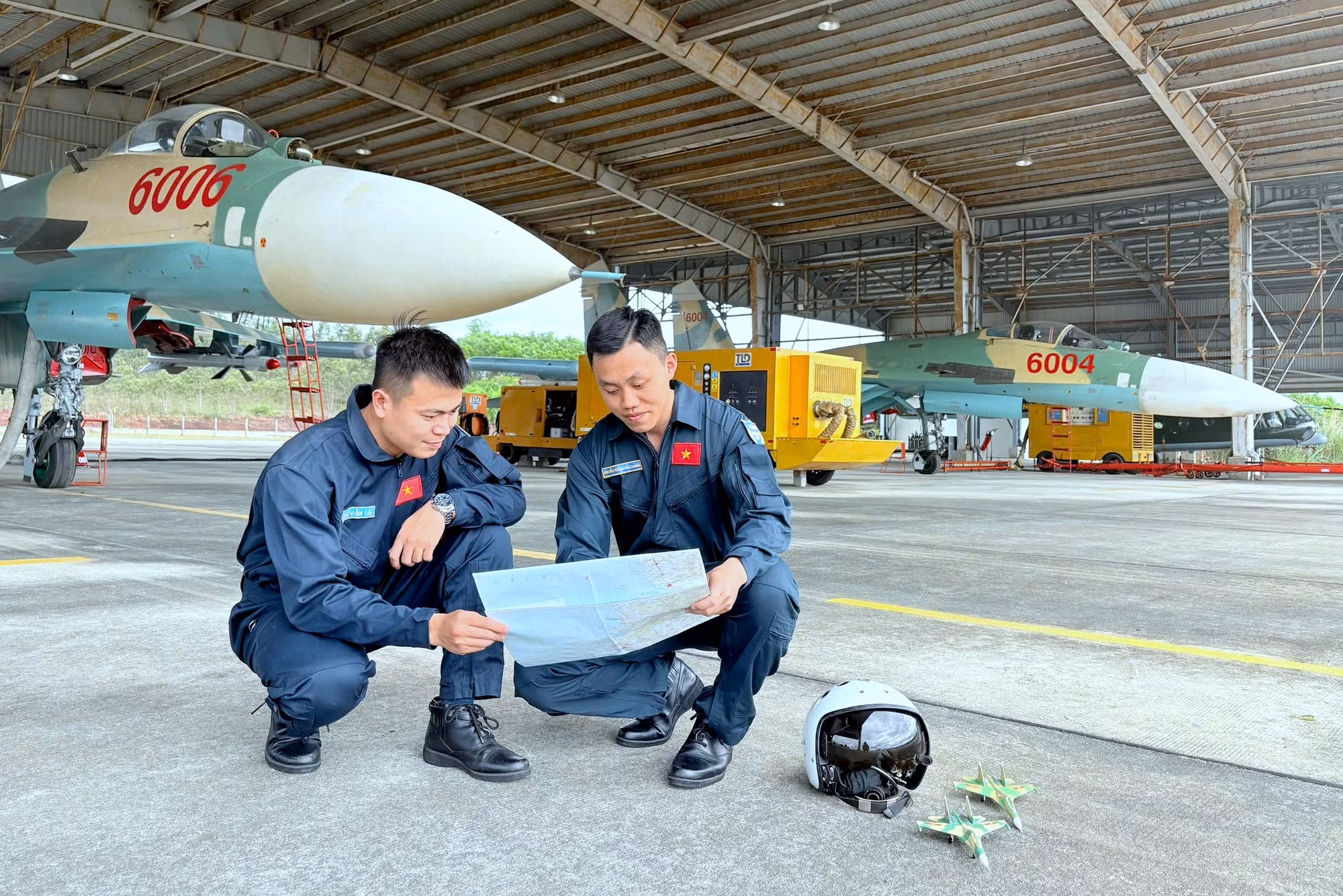 Đại úy Nguyễn Hoàng Hải Quang (bên phải) cùng đồng đội rút kinh nghiệm sau chuyến bay.