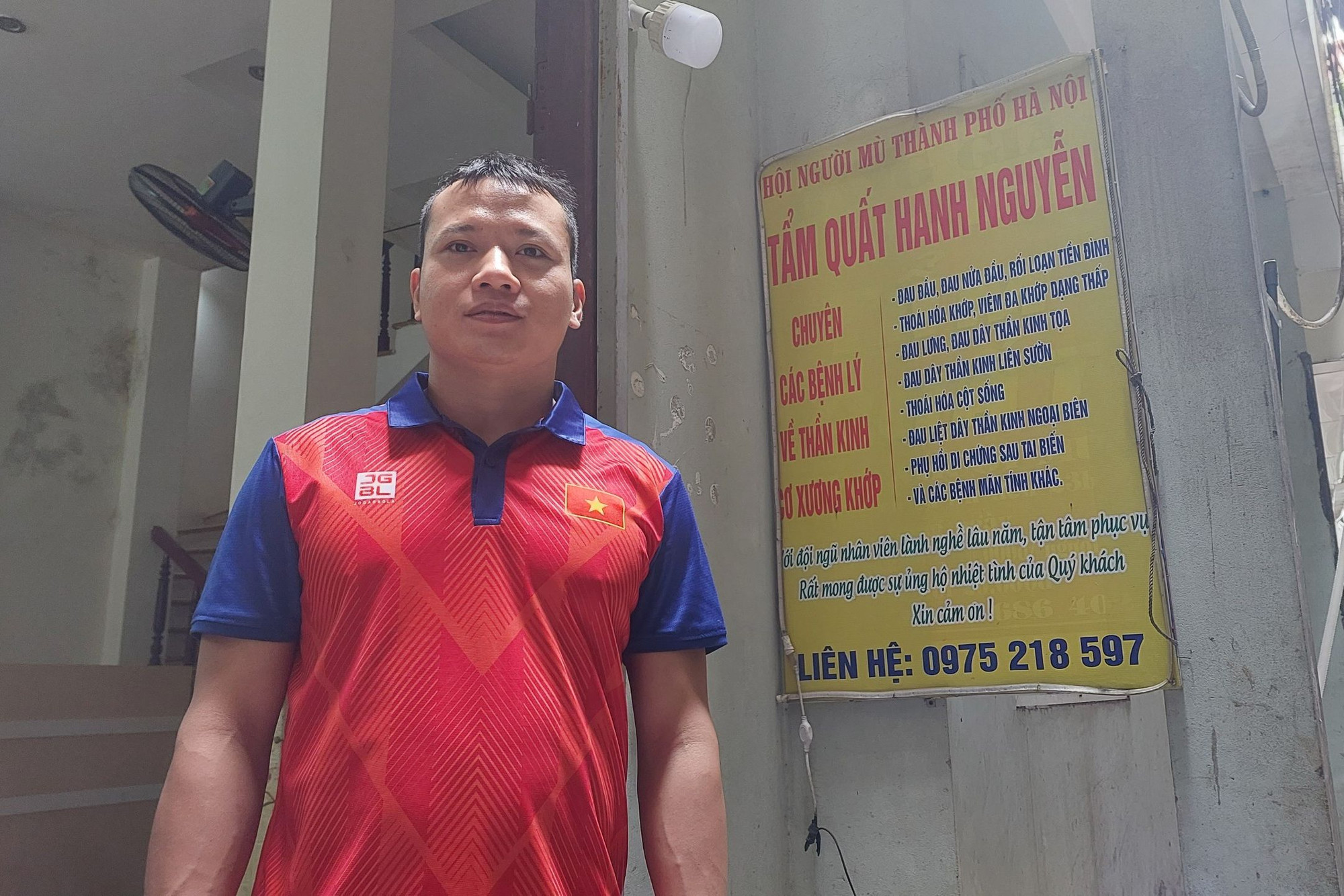 Nguyễn Văn Hanh trước cơ sở xoa bóp bấm huyệt trong con ngõ nhỏ trên đường Đê La Thành.