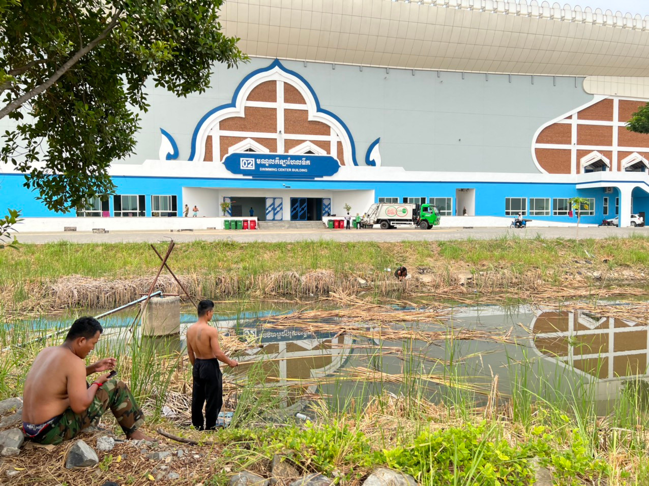 Một số người dân nhàn tản câu cá ở hồ nước bên cạnh nhà thi đấu.