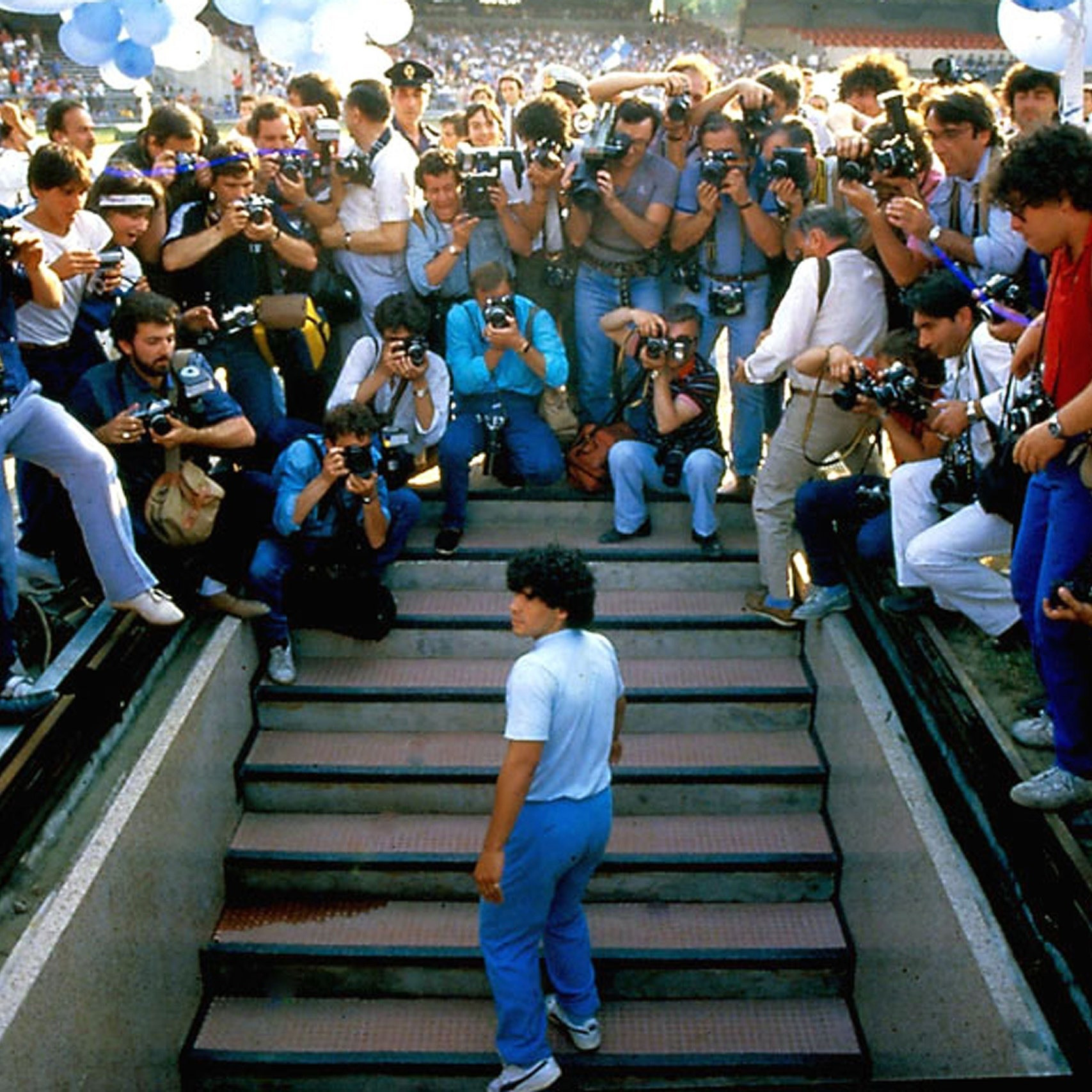 Maradona trong chiếc quần chinos màu xanh và áo phông trắng trong lễ ra mắt Napoli năm 1984.
