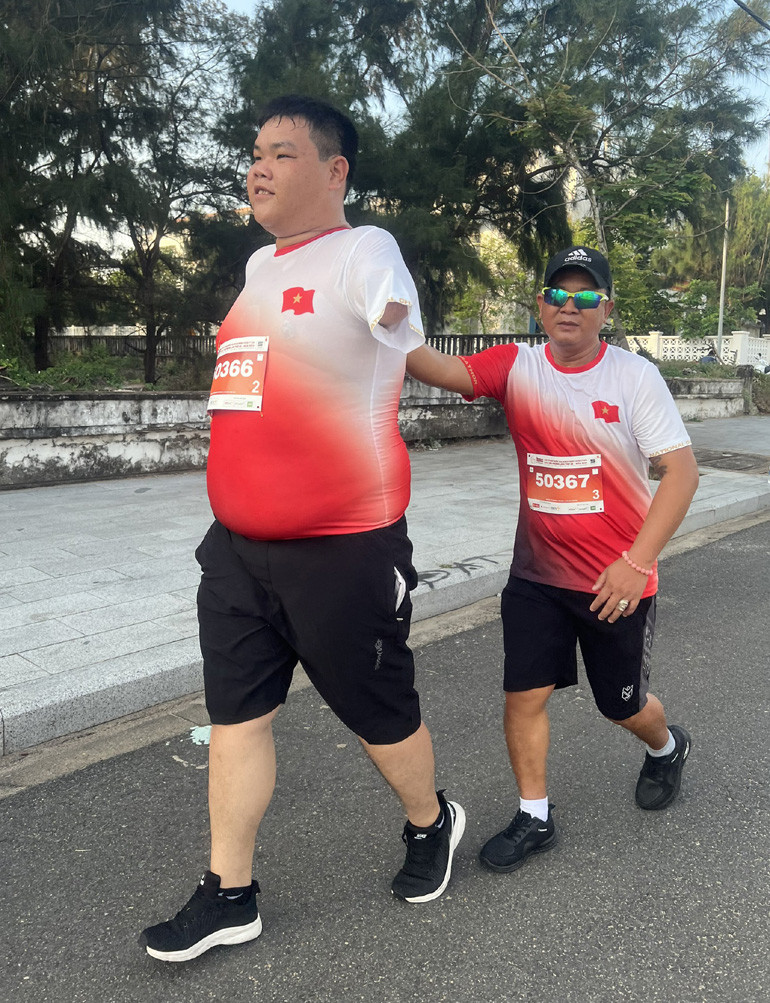 Anh Phan Văn Sanh bám vào lưng đồng đội Phan Tấn Minh Tâm tại Tiền Phong Marathon 2024.