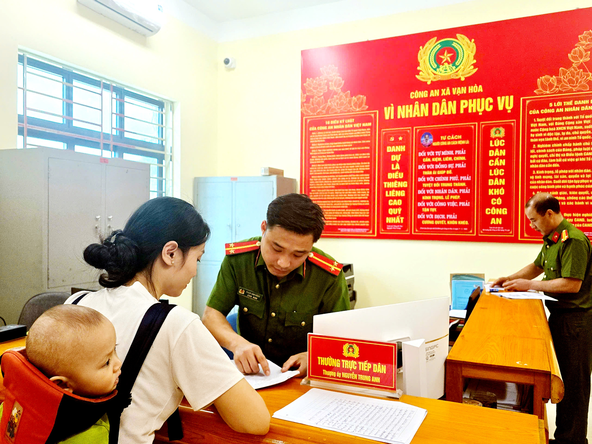 Cán bộ công an xã hướng dẫn người dân làm thủ tục trên smartphone Cán bộ công an xã hướng dẫn người dân làm thủ tục trên smartphone