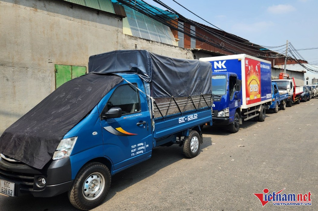 Ô tô đậu hàng dài trước cổng trung tâm đăng kiểm 50-07V, tài xế phải phủ bạt chống nóng cho xe.