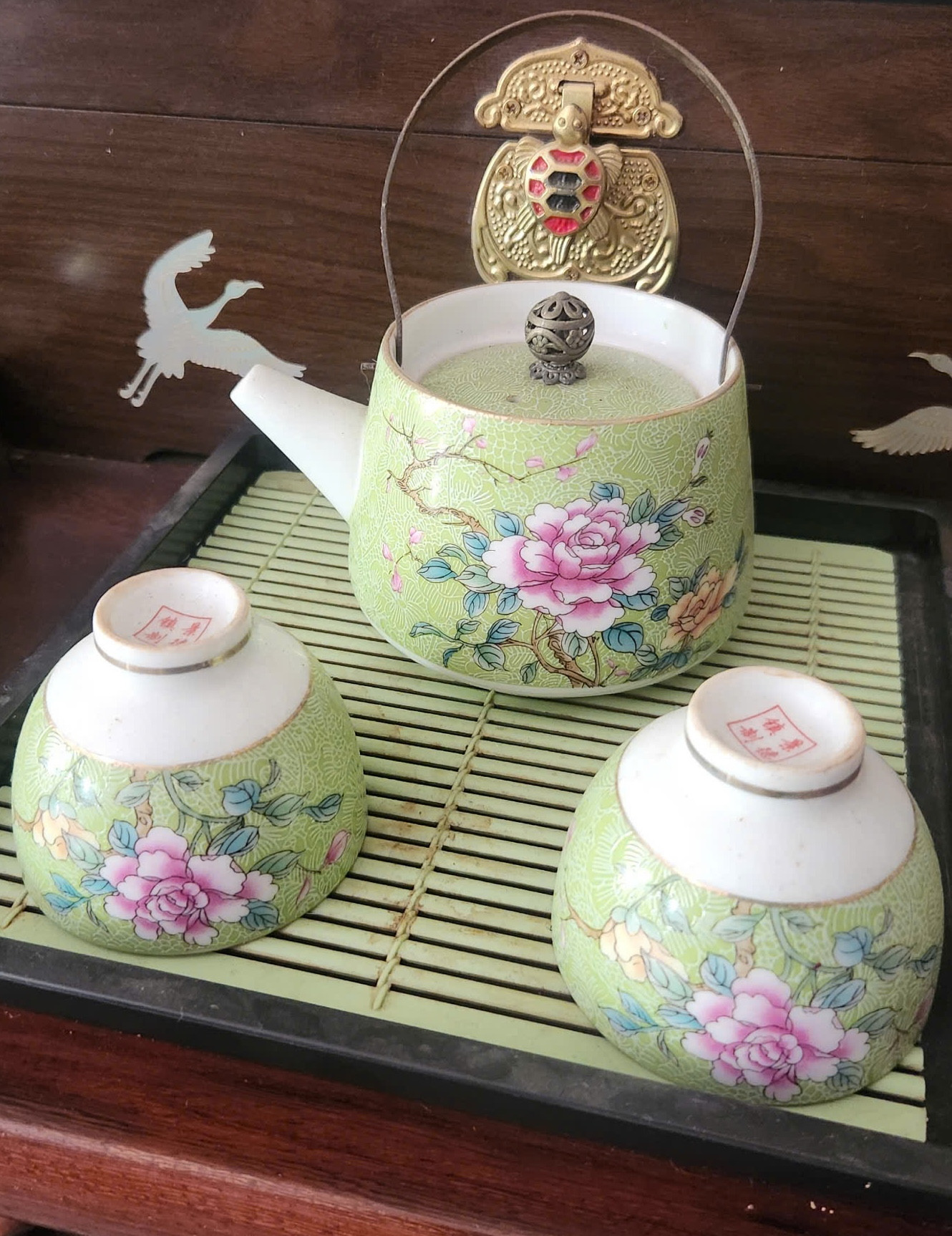 Ấm trà và ly với những hoạ tiết hoa lá trên nền men nhám Ấm trà và ly với những hoạ tiết hoa lá trên nền men nhám