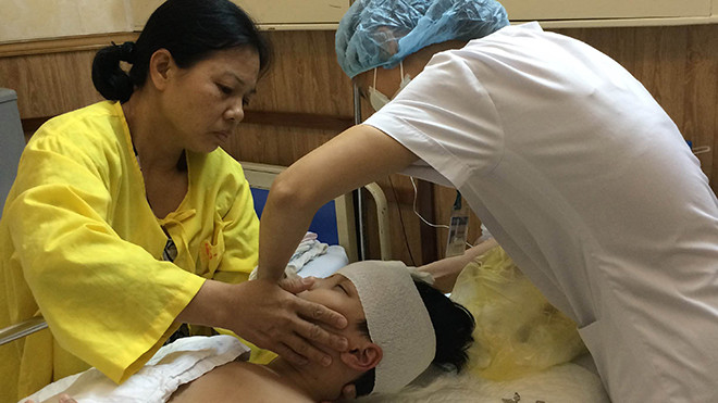 Chị Dũng (bìa trái) động viên con trai trong lúc điều dưỡng thay băng cho bé